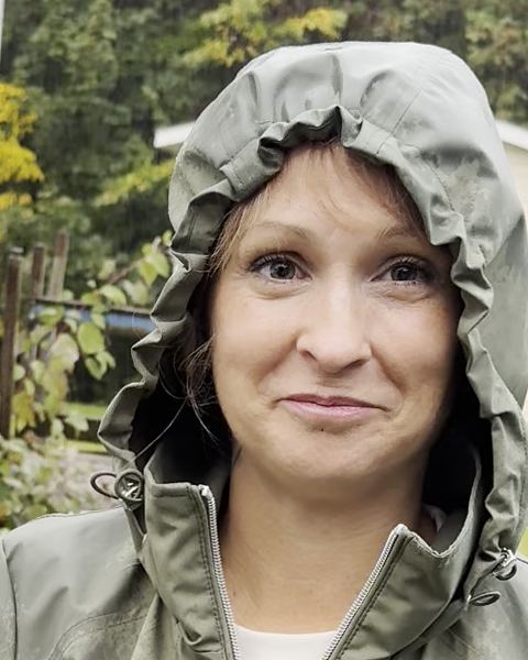 Stéphanie Portelance smiles at the camera from under the hood of a green rain jacket.